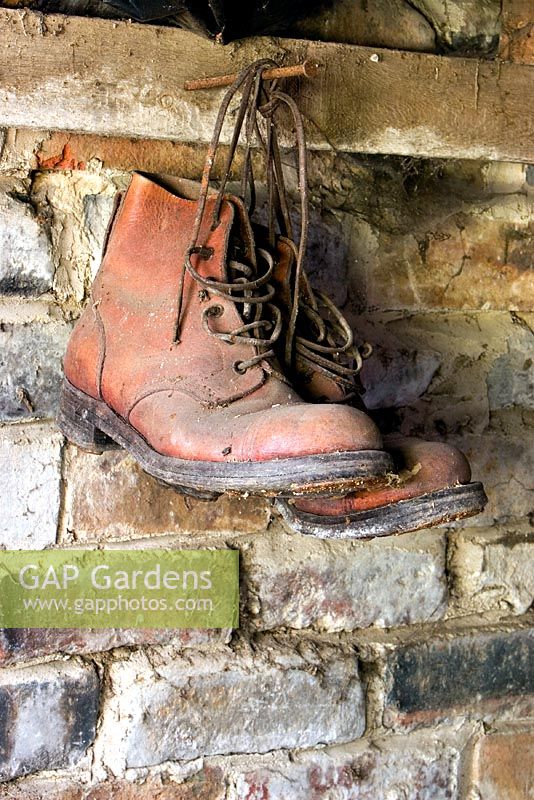 Old gardening boots hanging in shed from a rusty nail