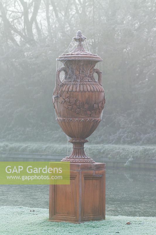 Terracotta urn with cobwebs in fog and frost