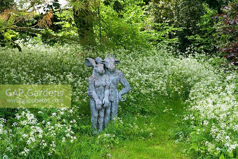 Statues hidden amongst cow parsley at edge of garden, Barnsley House Gardens, Glos - Former garden of Rosemary Verey 

