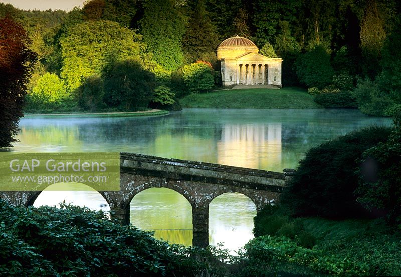 Early morning with bridge over lake and The Temple Pavilion on the far side reflected in the water - Stourhead, Stourton, Wilts 