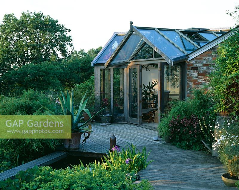 View of deck with pool, Agave americana in container and garden room behind - The Fovant Hut, Wiltshire