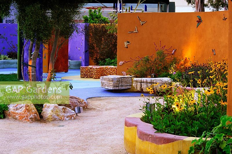 Contemporary colourful childrens garden with raised beds and orange wall 