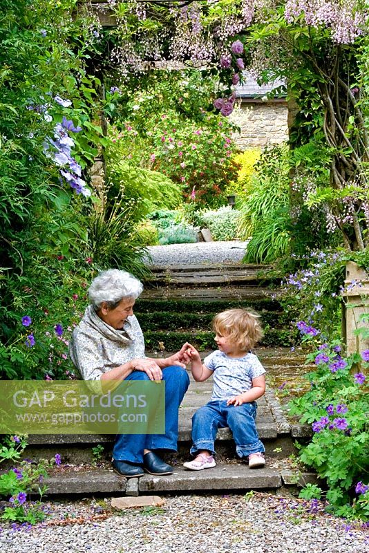 Grandmother and grandaughter sitting under a Wisteria covered pergola