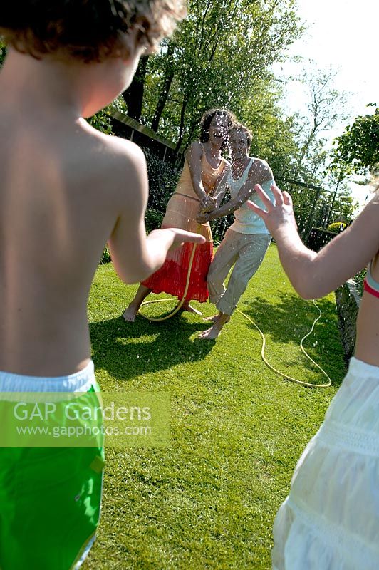 Family playing with hose in garden 