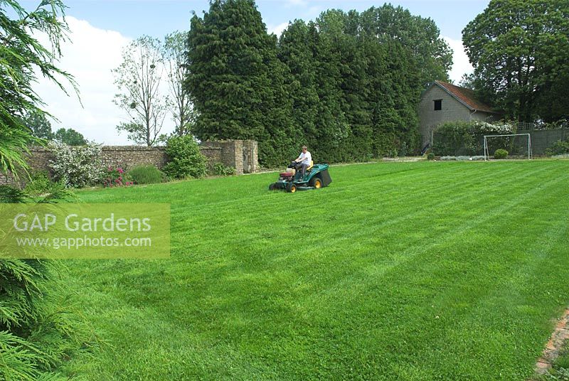 Boy on ride on mower in French walled garden