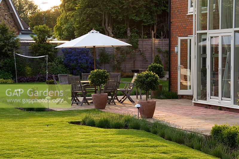 Patio with furniture and umbrella beside  house at Richard Jacksons garden