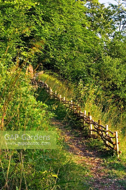 Path into woodland, woven fence made with natural wood felled from the wood
