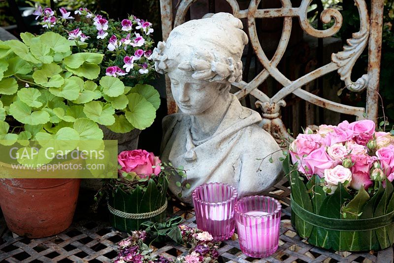 Arrangement with pink roses, candles and statue