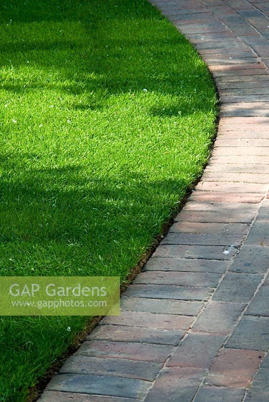 Curved Brick path with neatly edged lawn  in May