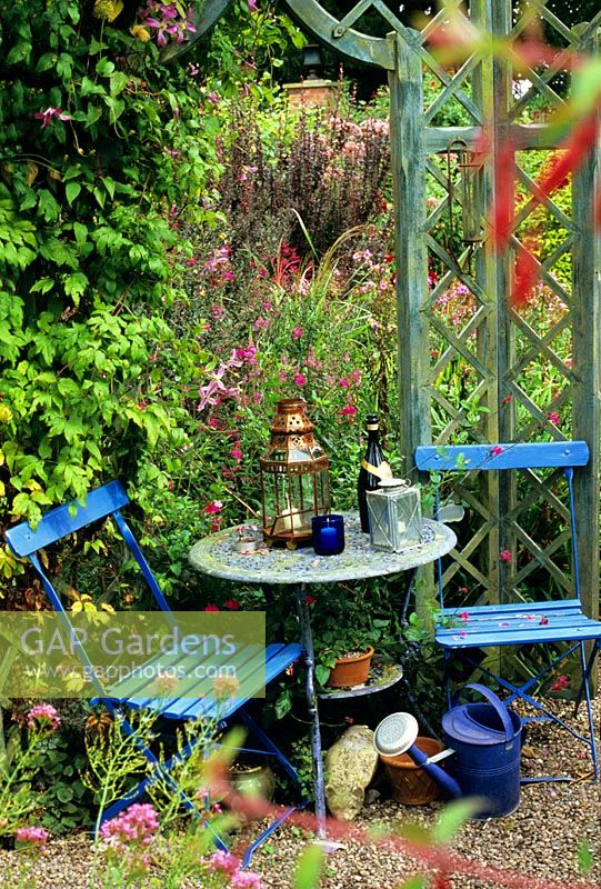 Rustic seating area with ornaments and watering can inside a gazebo