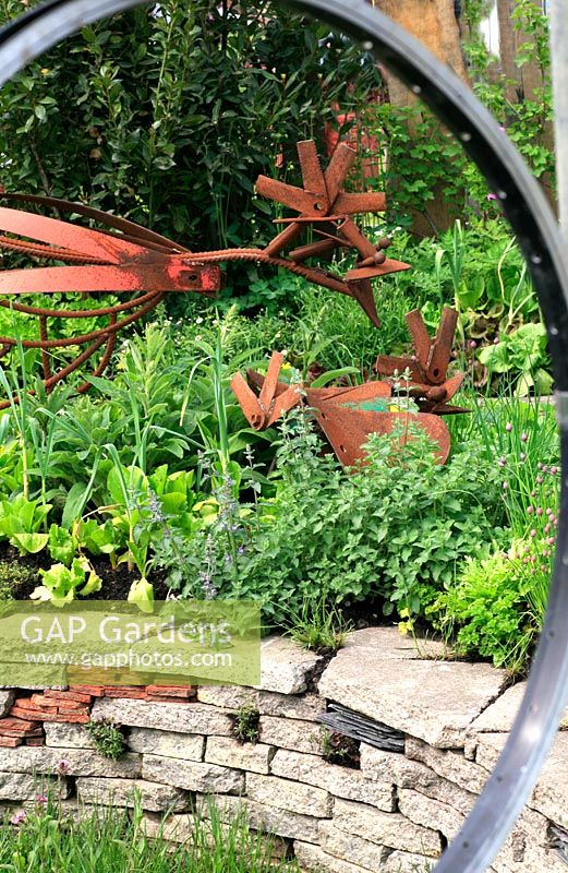 Garden built from recycled materials - Windows made from bicycle wheels, chicken sculptures made from old mower parts and underplanted with vegetables and herbs