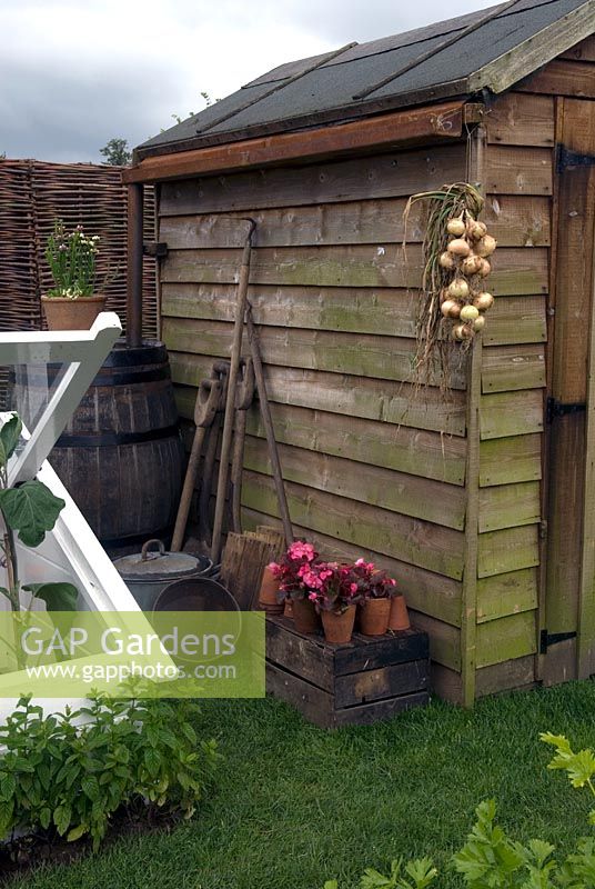 Garden shed with water butt and cold frame. Garden tools and onions hanging to dry - Hampton Court Flower Show 2007