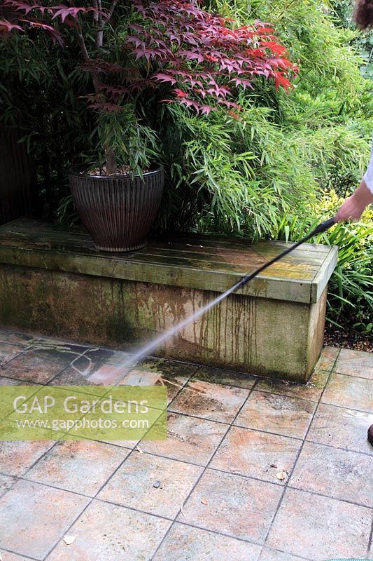 Pressure washing tiled patio garden to remove moss and algae