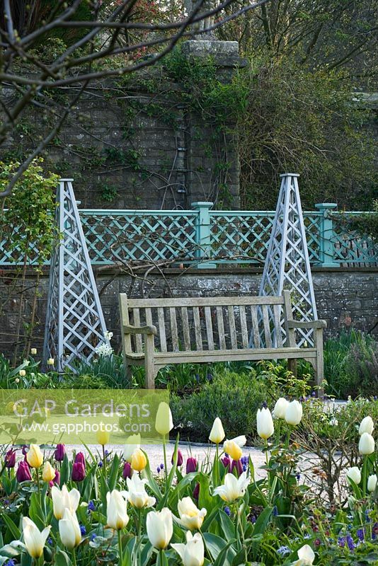 The sunken garden in Spring with Tulips, wooden tripods and wooden bench - Holker Hall, Cumbria