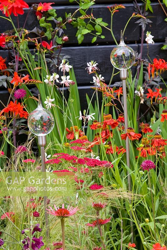 Warm colour border with Crocosmia, Allium, Echinacia, Stipa tenuissima and glass reflecting globes - Benecol's Prism Corner Garden - supporting Rainbow Trust - RHS Hampton Court Flower Show 2008 
