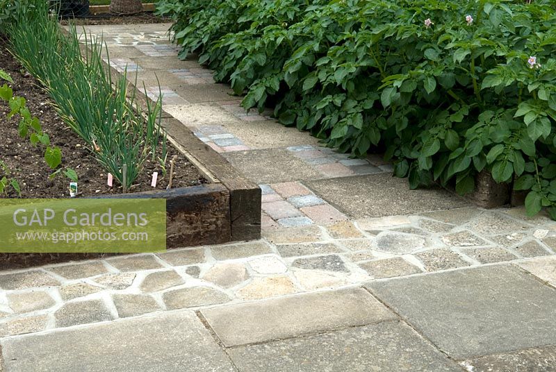 Recycled old slabs, sets and broken slabs to create hard paths around raised beds with wheelchair access in mind