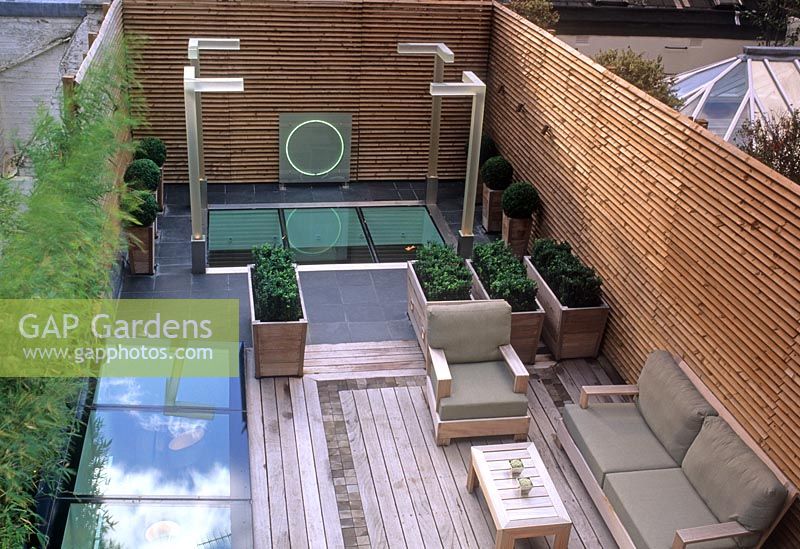 Contemporary rooftop garden with decking, seating, lighting and Buxus spheres in containers - Wilton Place, London