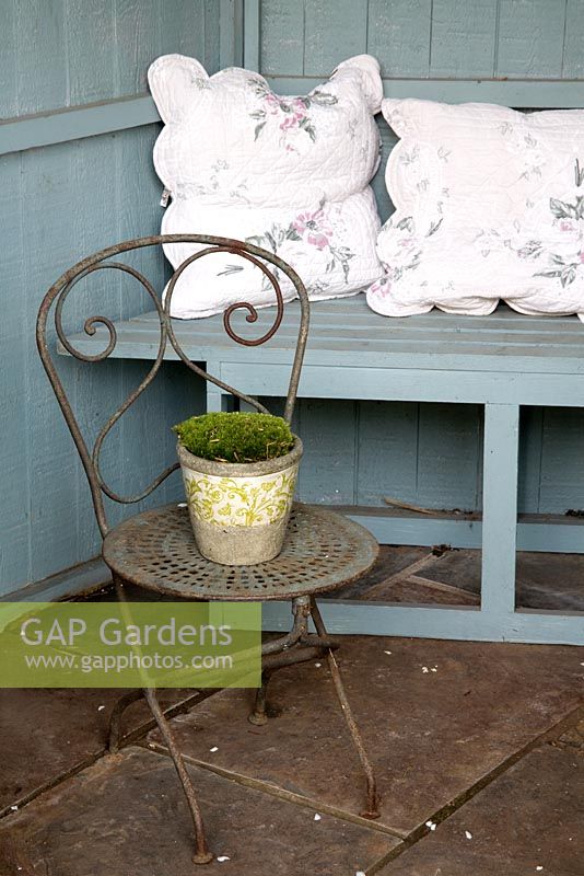 Summerhouse interior with old ornamental  chair and glazed pot of Mind-your-own-business 