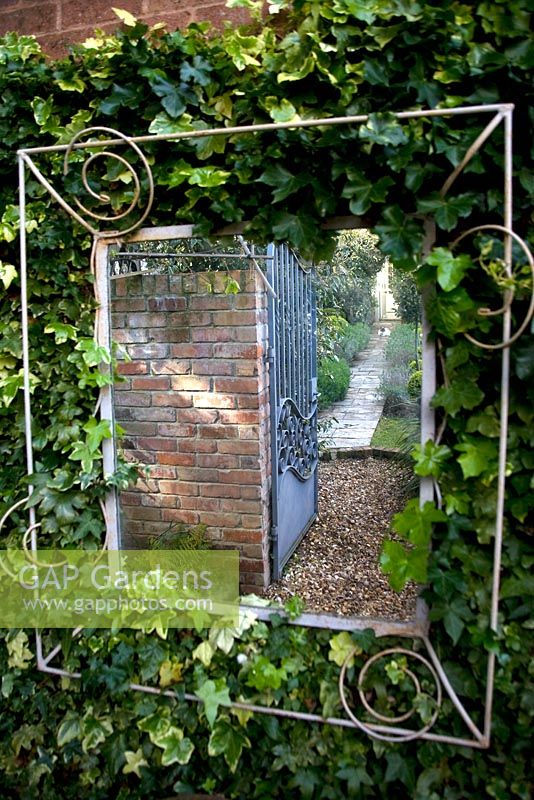 Mirror on Ivy covered wall, reflecting a pathway to increase the size of a small urban garden 