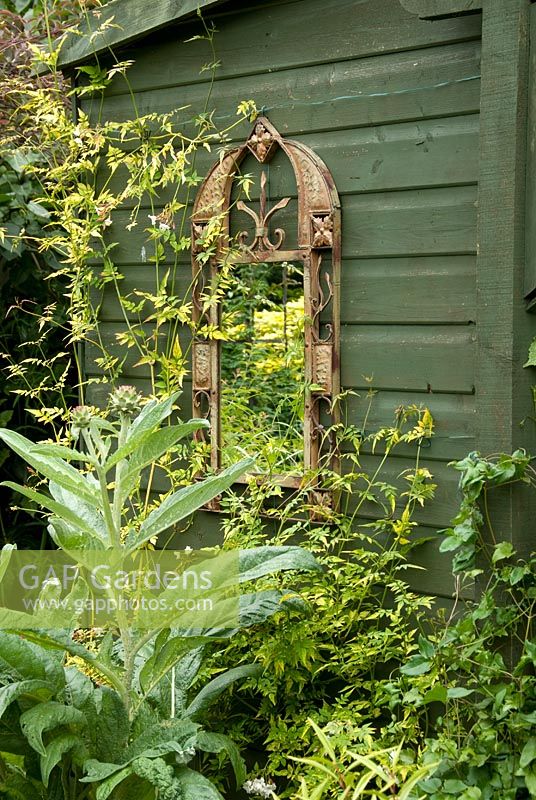 Framed mirror set upon green shed wall