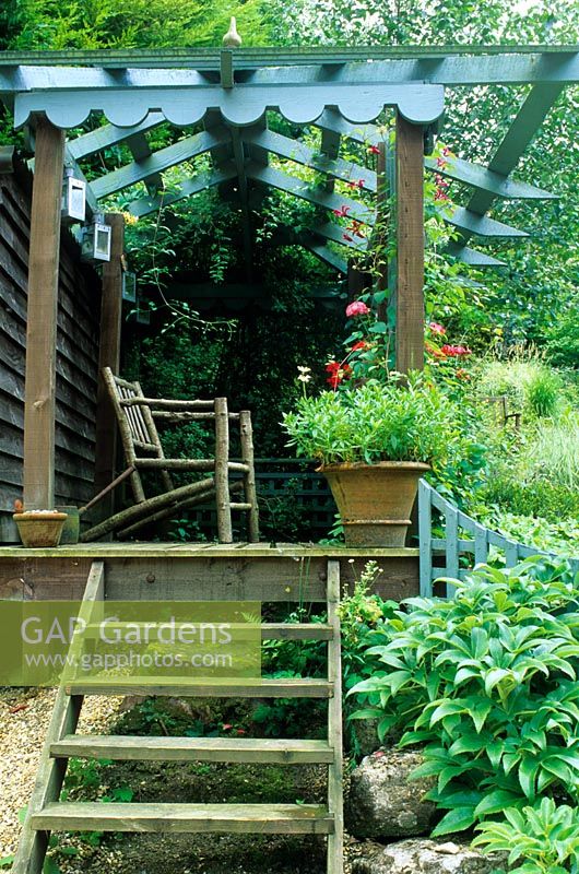 Garden in August with steps leading up to a blue painted summer house, designed by Alan Titchmarsh at Barleywood, Hampshire
