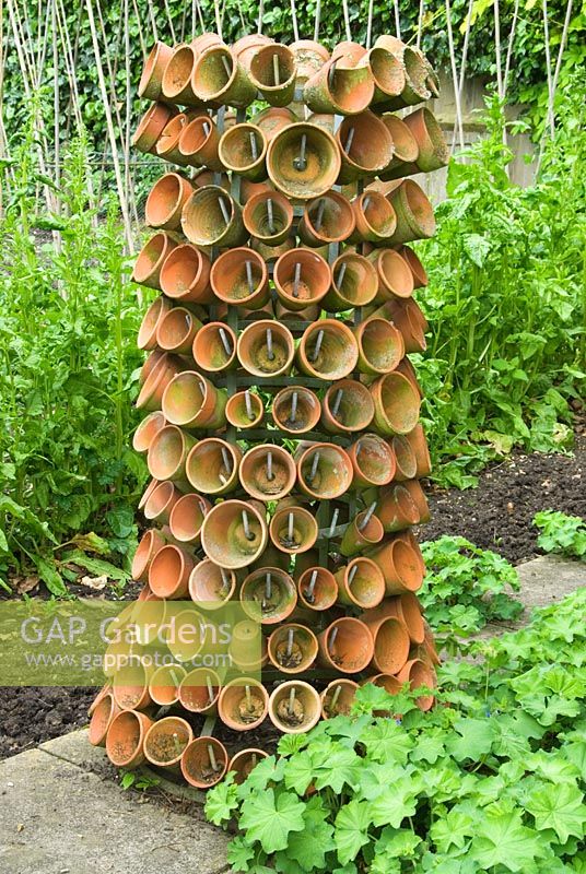 Bottle rack used to hang clay pots in private garden, Hampshire.