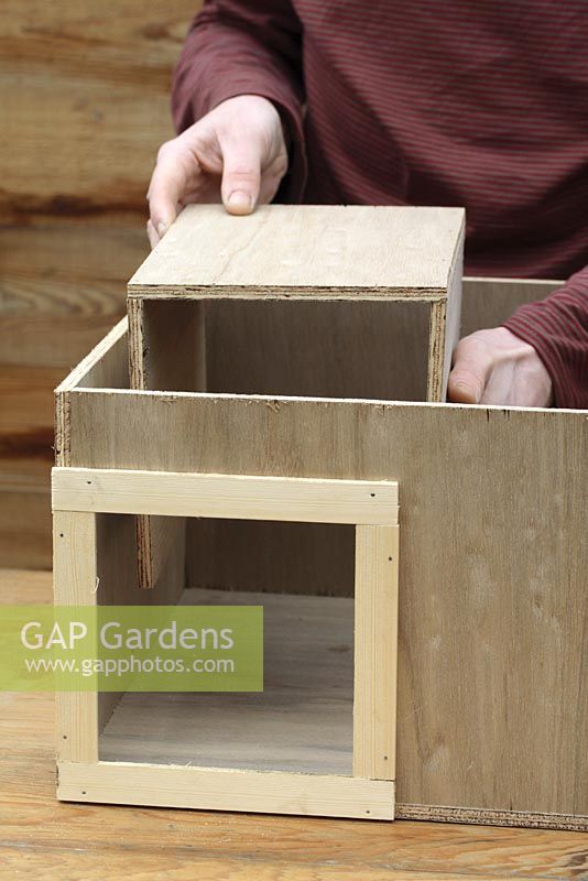 Step by step 5 of making a hedgehog house - Placing entrance tunnel, also made from plywood into wooden box