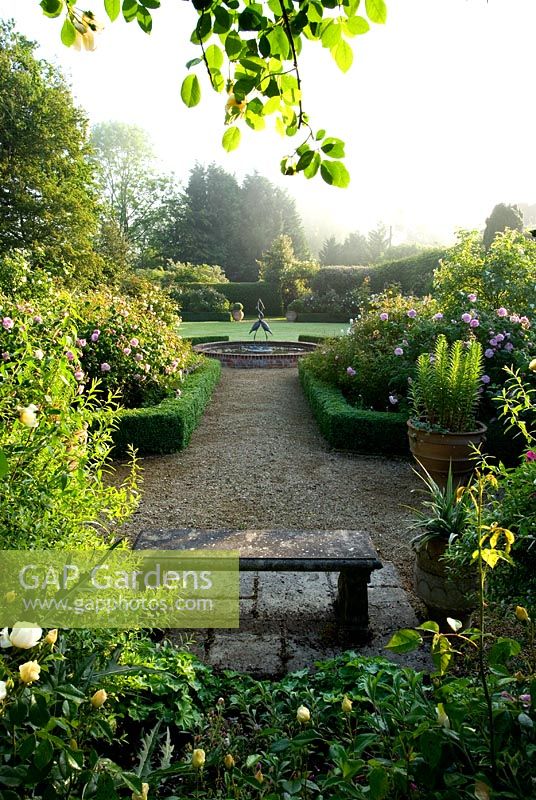 View into the rose garden to the water lily pool with heron sculpture - Mariners Garden, Berkshire