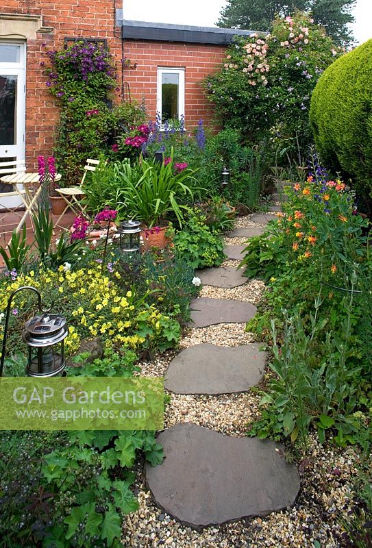 Patio beside house with cafe style table and chairs, gravel and stepping stone path, planting of Gladiolus communis Byzantinus and Aconitum - Cross Villas, Shropshire