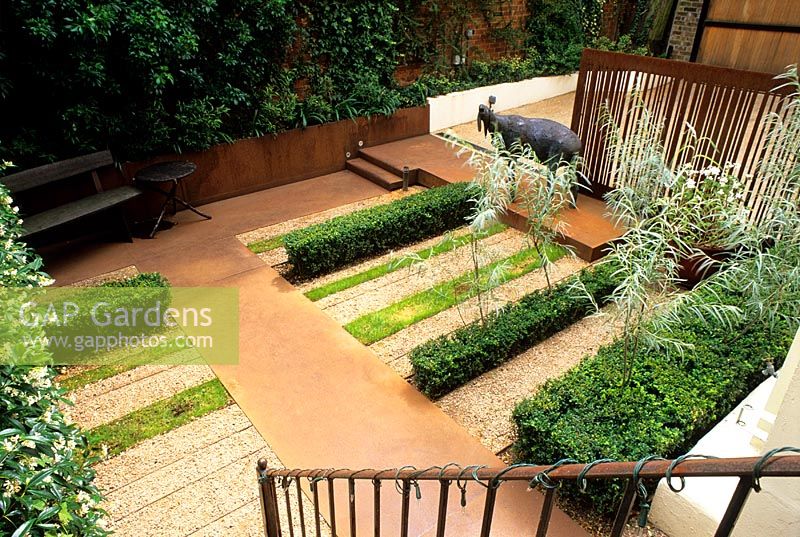 Corten steel predominates, used for the paths and stairs here. Strip plantings of lawn, box and gravel along with walls greened with climbers create a foil. Willows grow through the Buxus - Notting Hill Gate, London