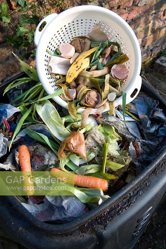 Plastic colander with food waste being added to compost bin