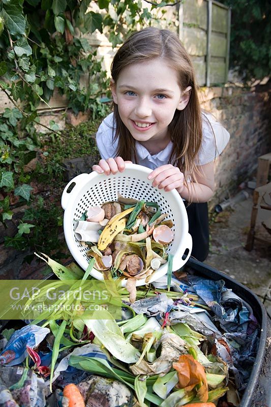 Girl emptying plastic colander with food waste in to the compost bin