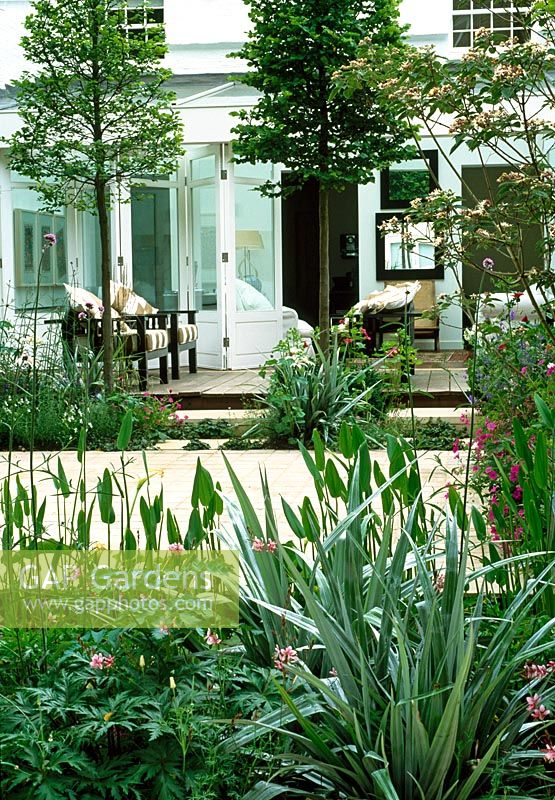 From this pale green garden apartment, sliding doors open onto an interior courtyard. The space is divided by pleached hornbeams and boarders of delicate perennials and Astelia chathamica.