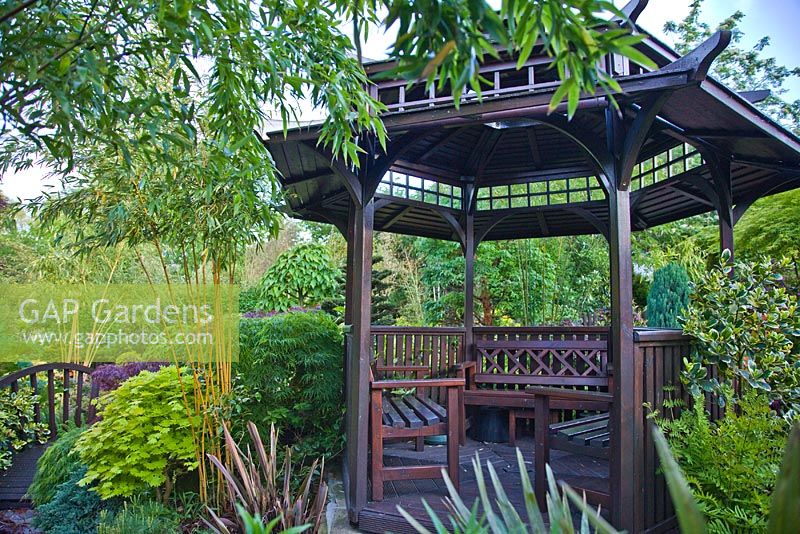 Pergoda with mature trees and shrubs in oriental themed garden at Four Seasons, NGS garden, Staffordshire