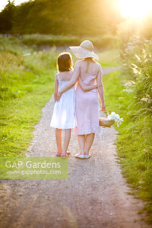 Woman holding basket of flowers with girl on path