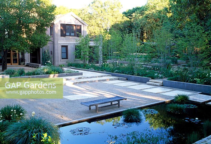 Pond and gravel with inset large pavers beside green and white planting in garden outside San Francisco