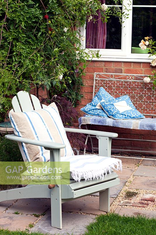 Adirondack garden chair and metal bench on a small patio in an urban garden