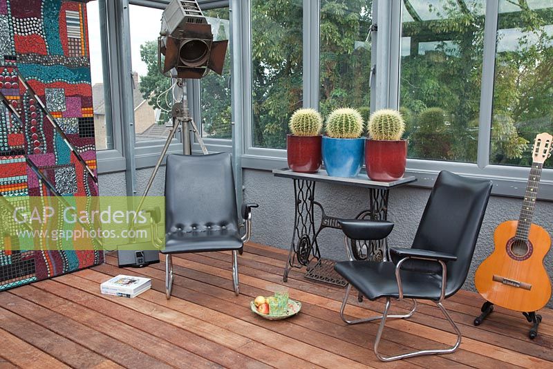 Retro vinyl chairs, old Singer table with Echinocactus grusonii in ceramic pots in roof terrace conservatory. Pop art inspired
mosaic by Yvonne Matthews and old BBC light, ipod and guitar - Roof Terrace Garden 