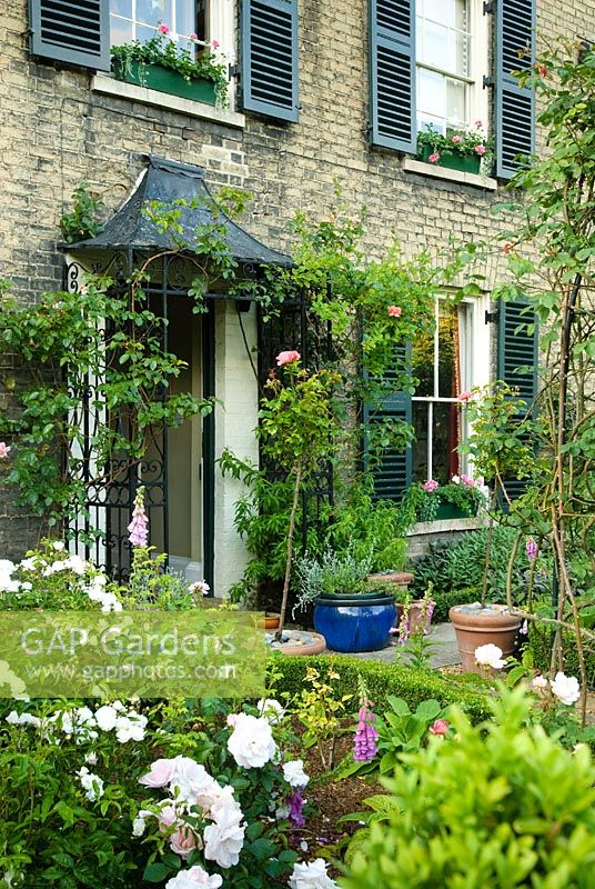 View across formal town garden to front door of Victorian house with shutters - New Square, Cambridge