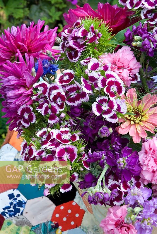 Colourful cut summer flowers in bucket on patchwork tablecloth - Dahlias, Zinnias, Mattiola incana, Nigella, Dianthus barbartus 
