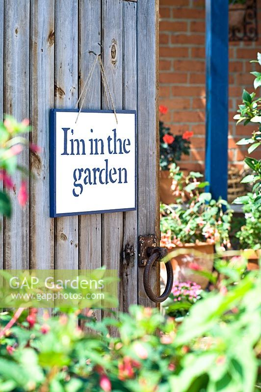 Hand stencilled sign hanging on wooden gate