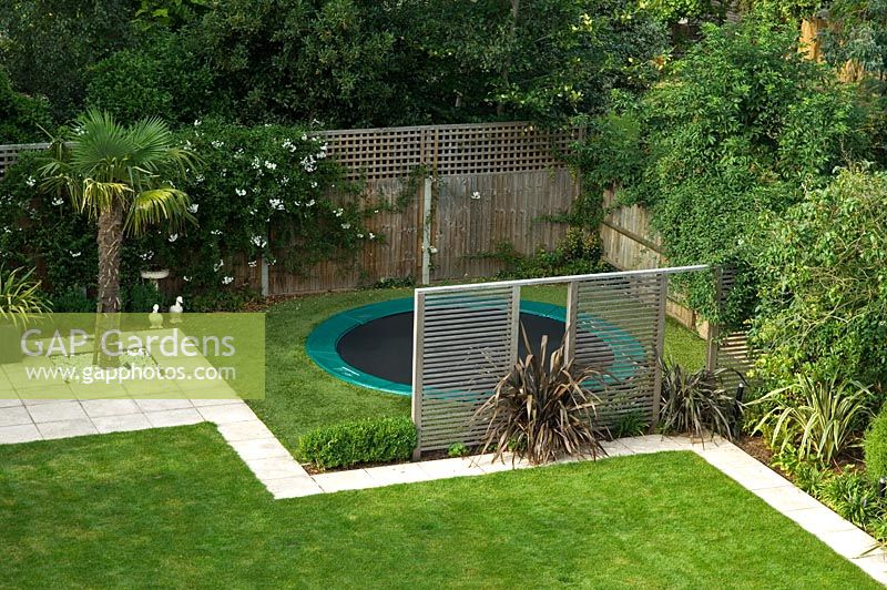 Contemporary urban garden with kids play area, astro turf lawn and mixed planting - London
