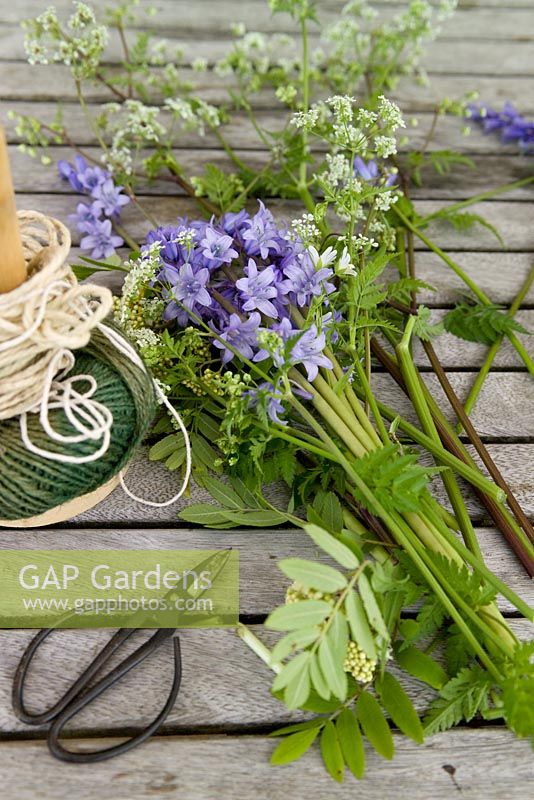 Picked bluebells and rowan foliage on a tabletop with twine 