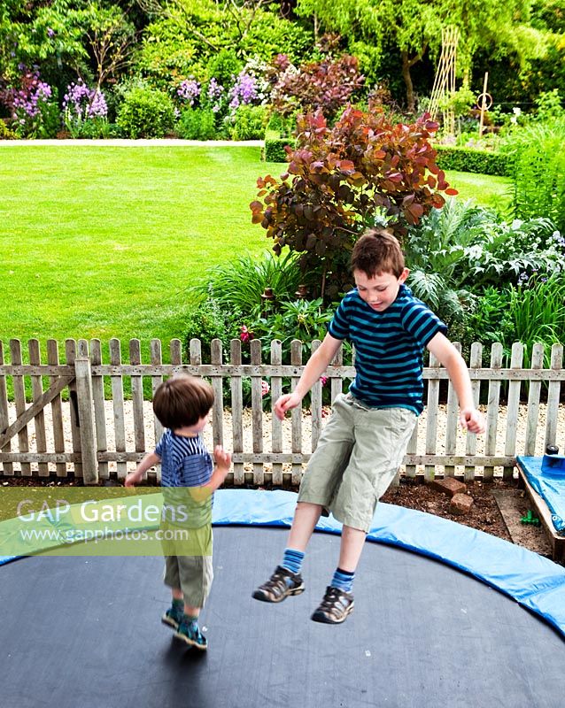 Children on trampoline at Mathern House, Mathern, Monmouthshire, Wales. Early June. Garden opens for National Gardens Scheme.