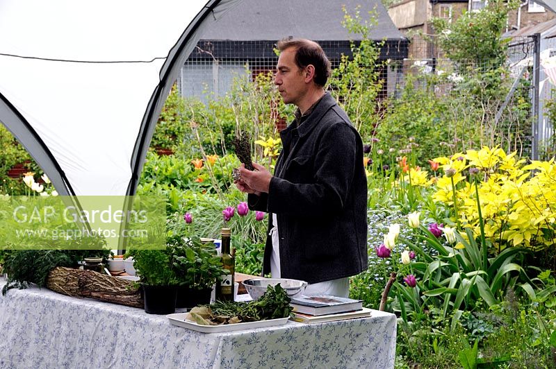 Chef demonstrating how to cook with herbs in a community garden 