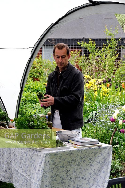 Chef demonstrating how to cook with herbs in a community garden
