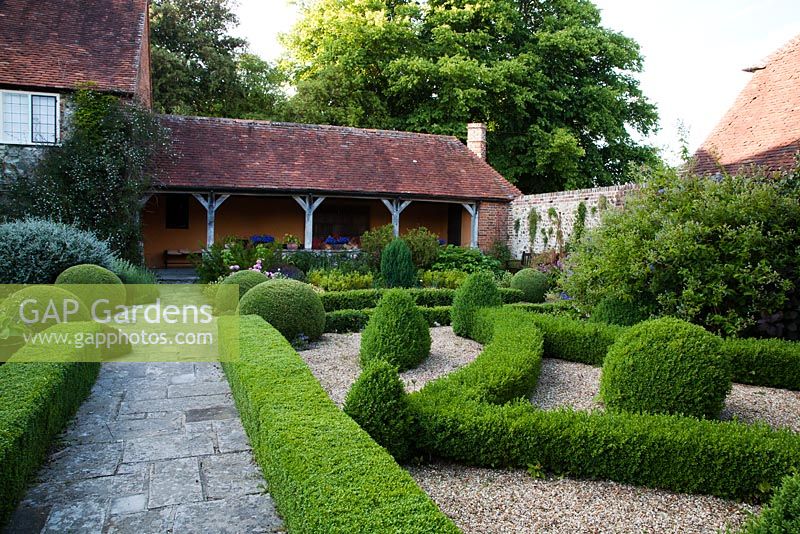 Stone pathway through formal topiary garden to verandah - Rymans, Sussex