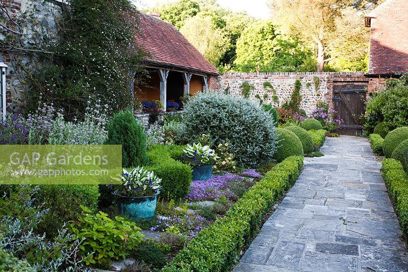 Stone pathway through formal parterre alongside mixed summer border - Rymans, Sussex