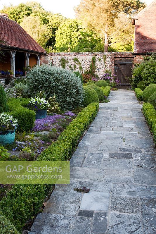 Stone pathway through formal parterre alongside mixed summer border - Rymans, Sussex