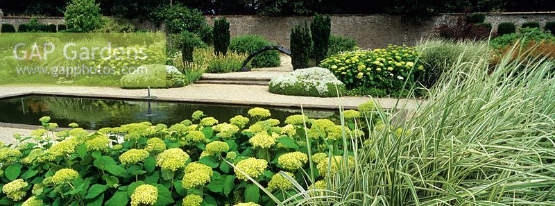 The White Garden at Loseley Park with planting including Hydrangea arborescens 'Annabelle', Miscanthus sinensis 'Variegatus', Sisyrinchium and Hebe